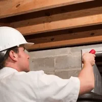 Termite inspection technician checking a basement wall and framing for termite activity in Cedar Rapids, IA